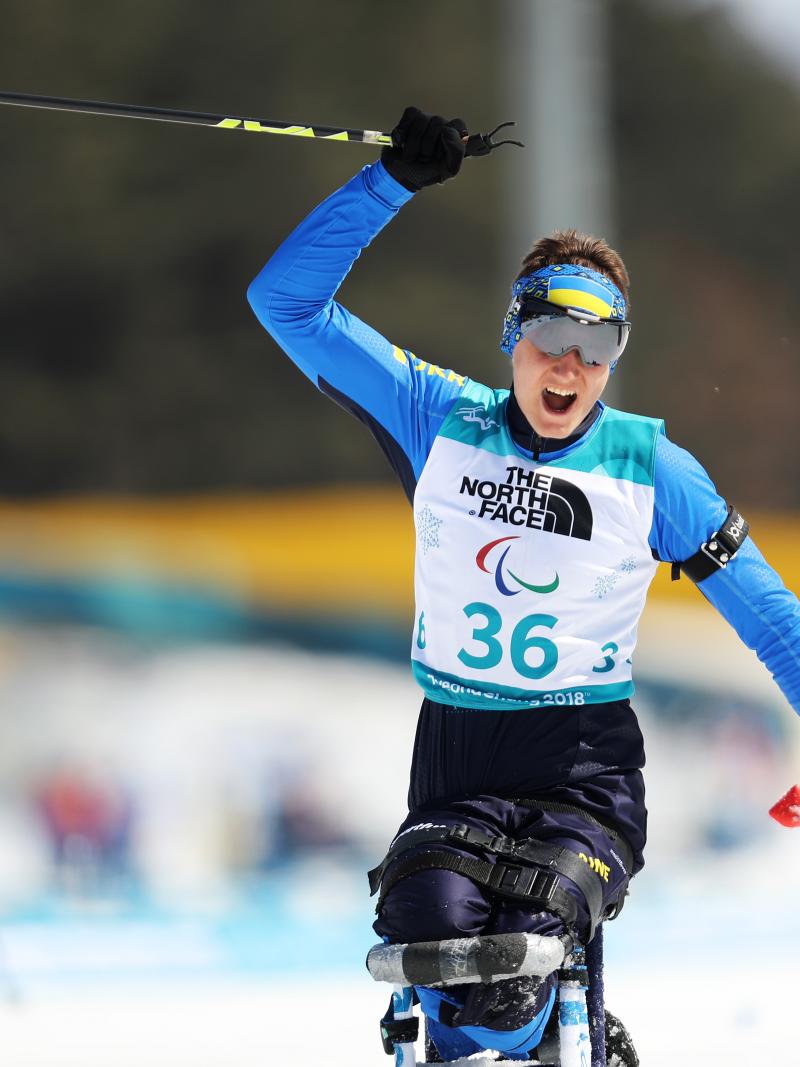 a male Para sit skier crosses the line and celebrates