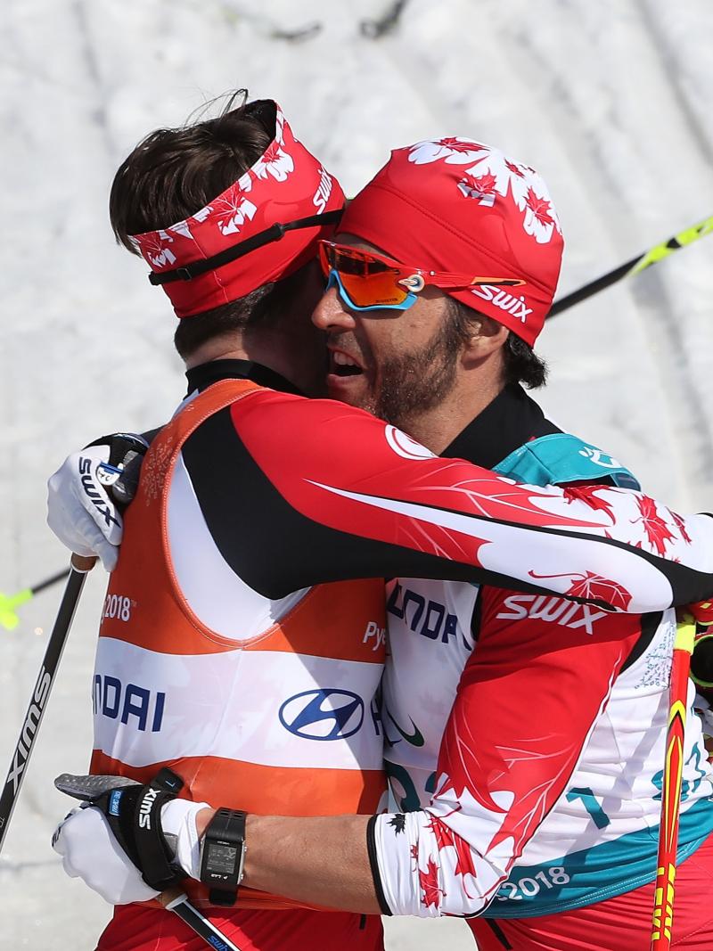 a visually impaired skier and his guide hug on the finish line