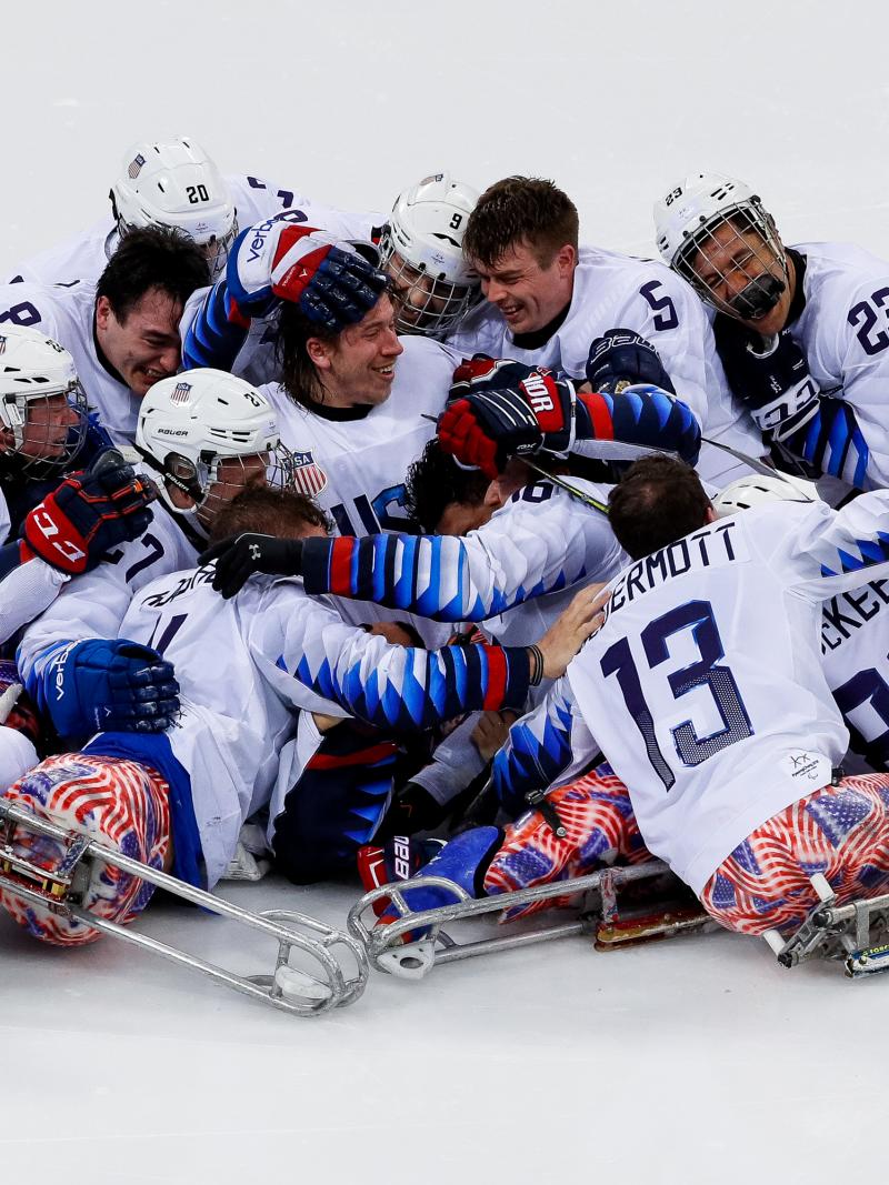 a group of Para ice hockey players in a heap on the ice