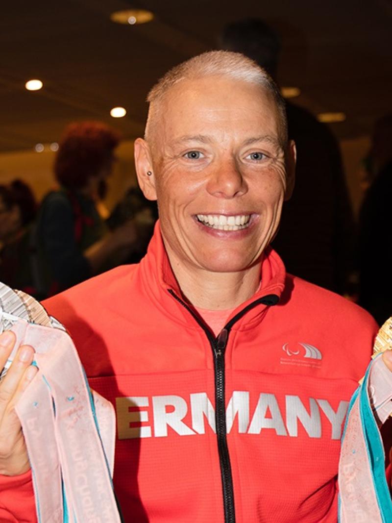 a female athlete holds up her six Paralympic medals