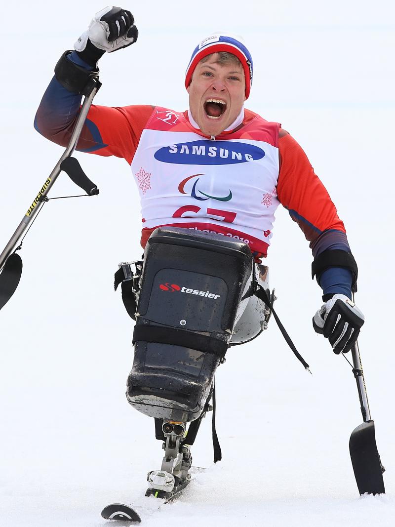 a male sit skier punches the air in celebration