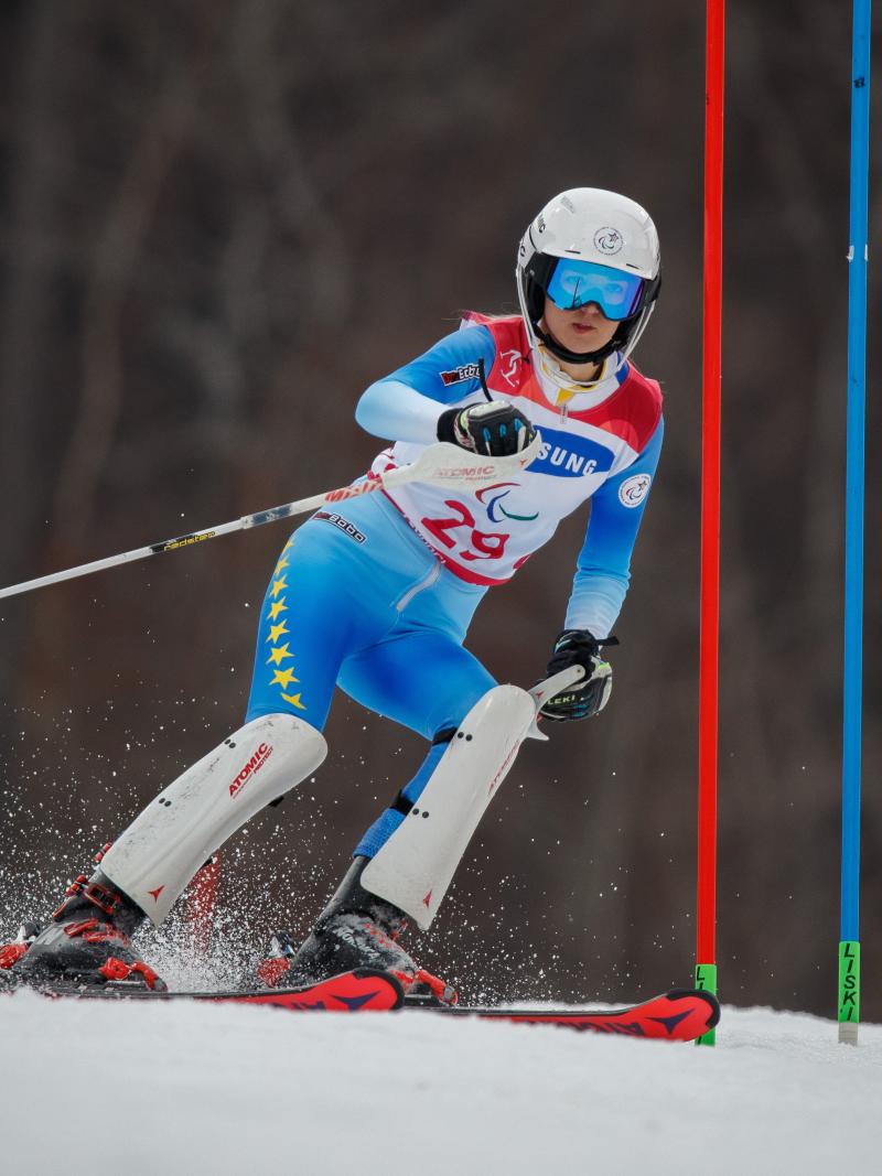 a female standing skier goes through a gate