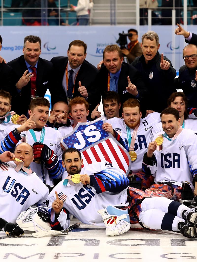 a group of Para ice hockey players celebrate with their gold medals