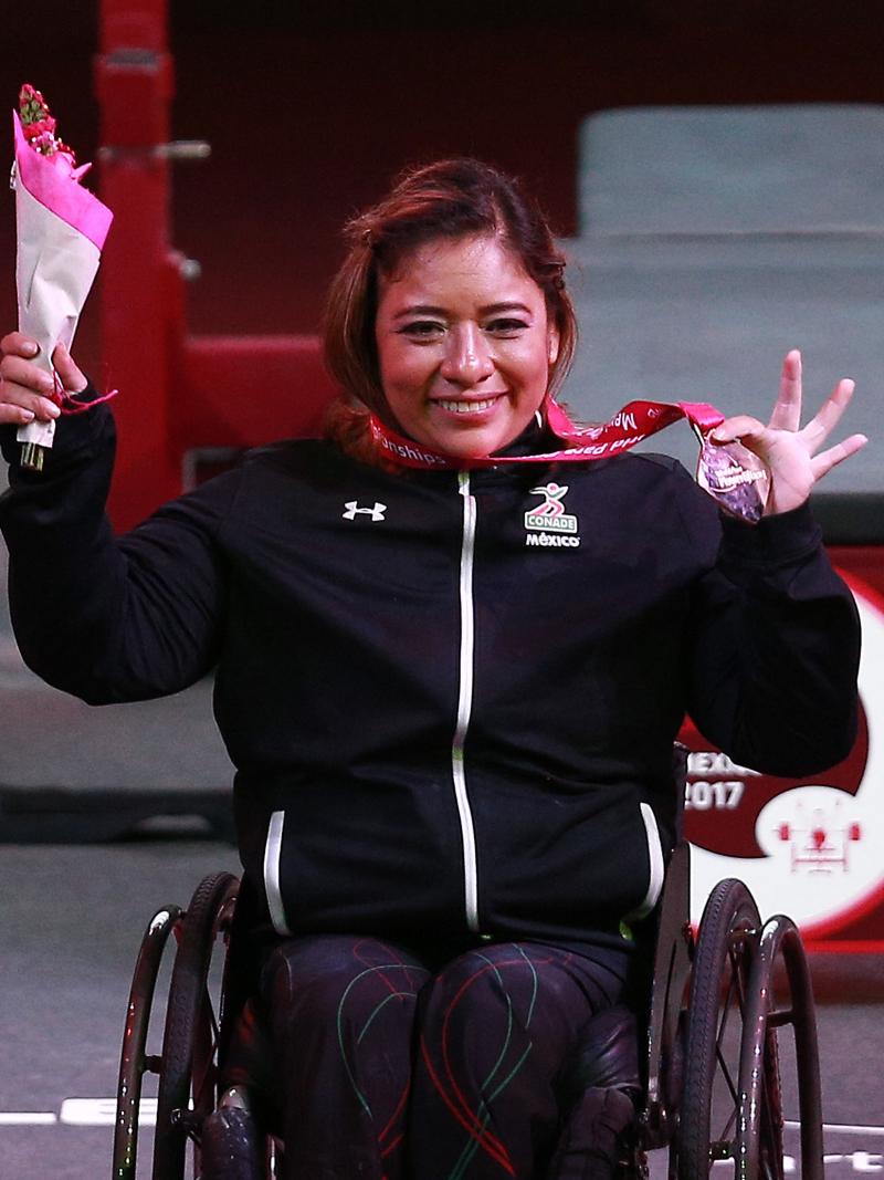 a female powerlifter holds up her gold medal