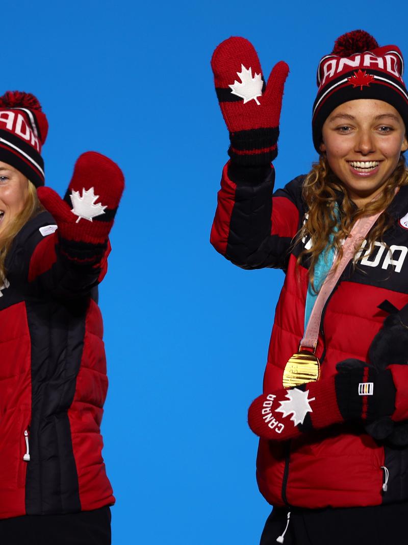 two female Nordic skiers wave from the podium