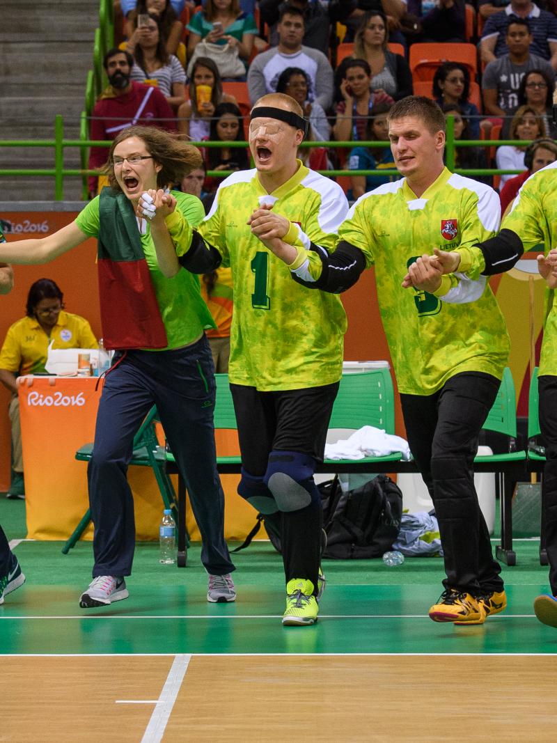 a group of goalball players link arms in celebration