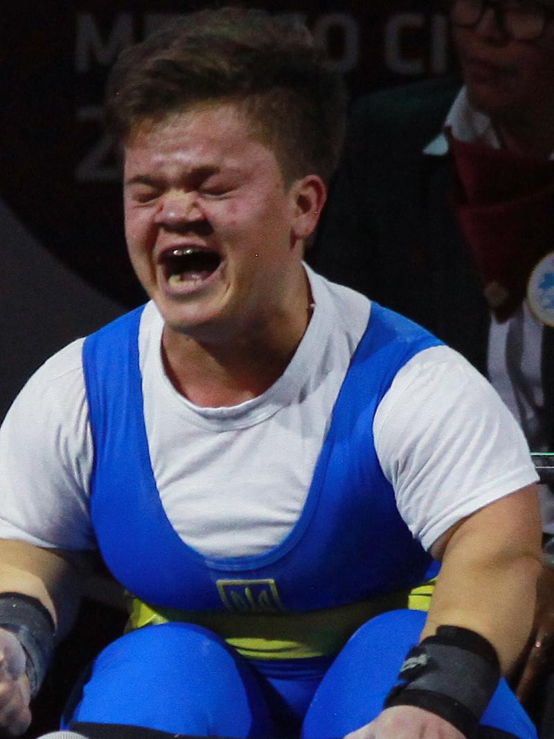 a female powerlifter clenches her fists on the bench