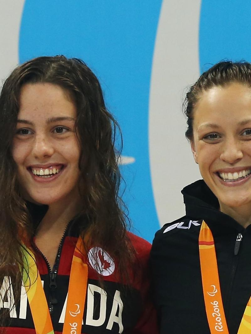 two female Para swimmers smiling on the podium