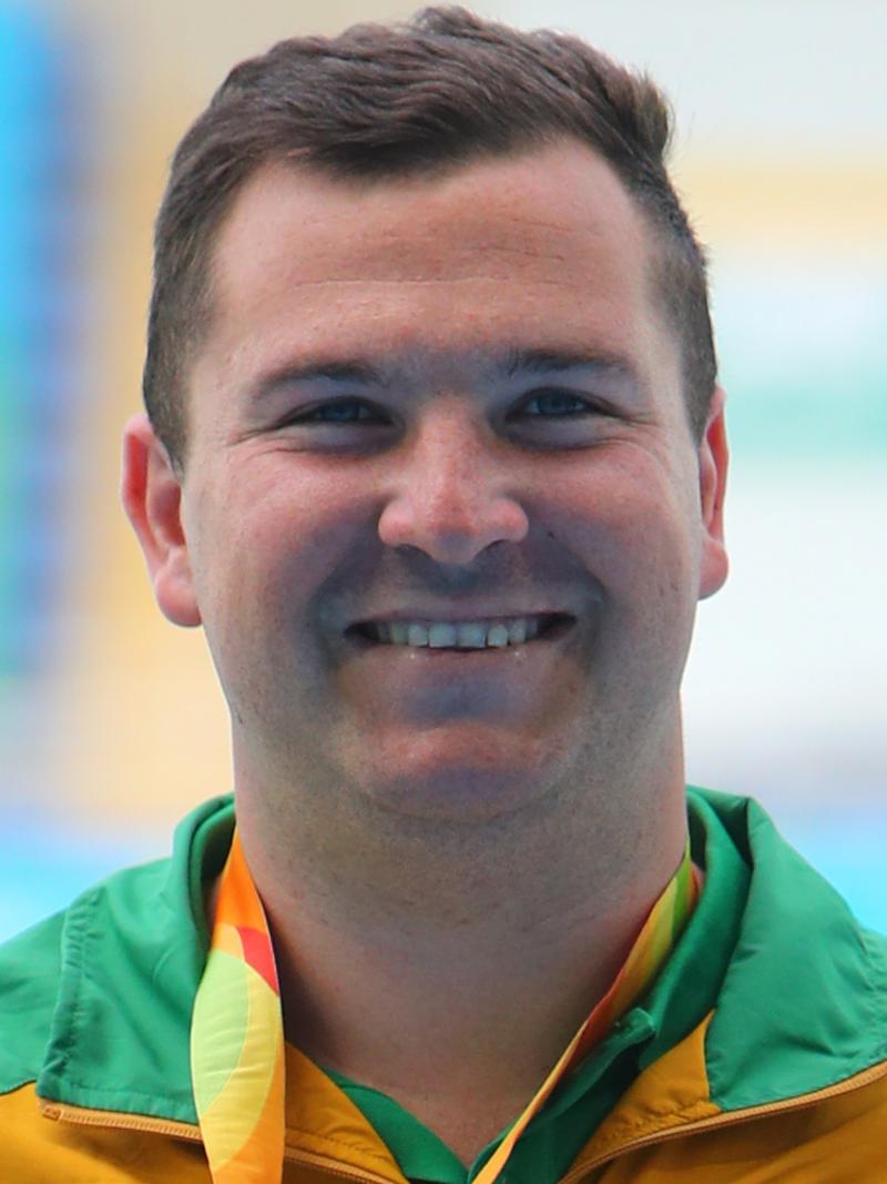 a male athlete smiling on the podium