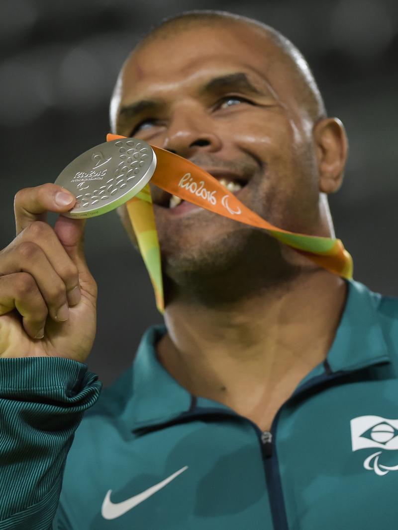 a male judoka holds up a silver medal