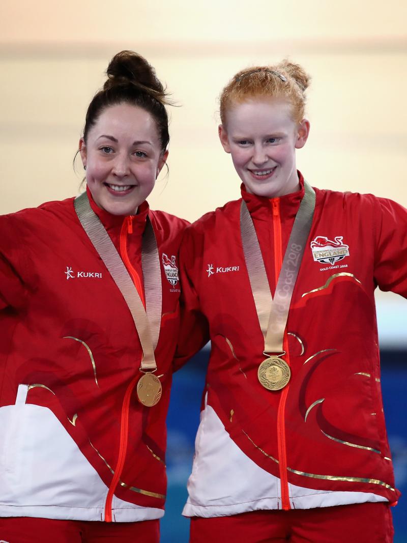 two female Para cyclists stand on the podium with their gold medals