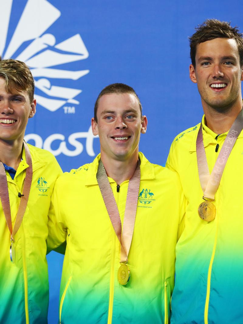 three male swimmers on the podium
