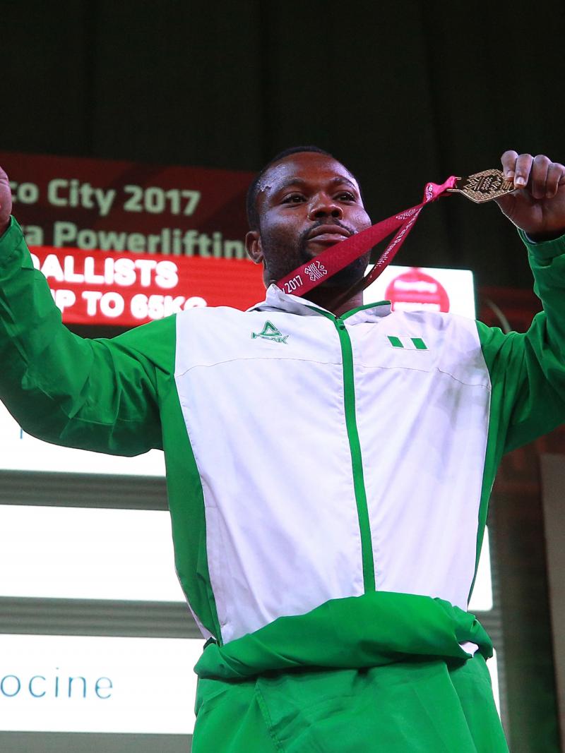 a male powerlifter holds up his gold medal