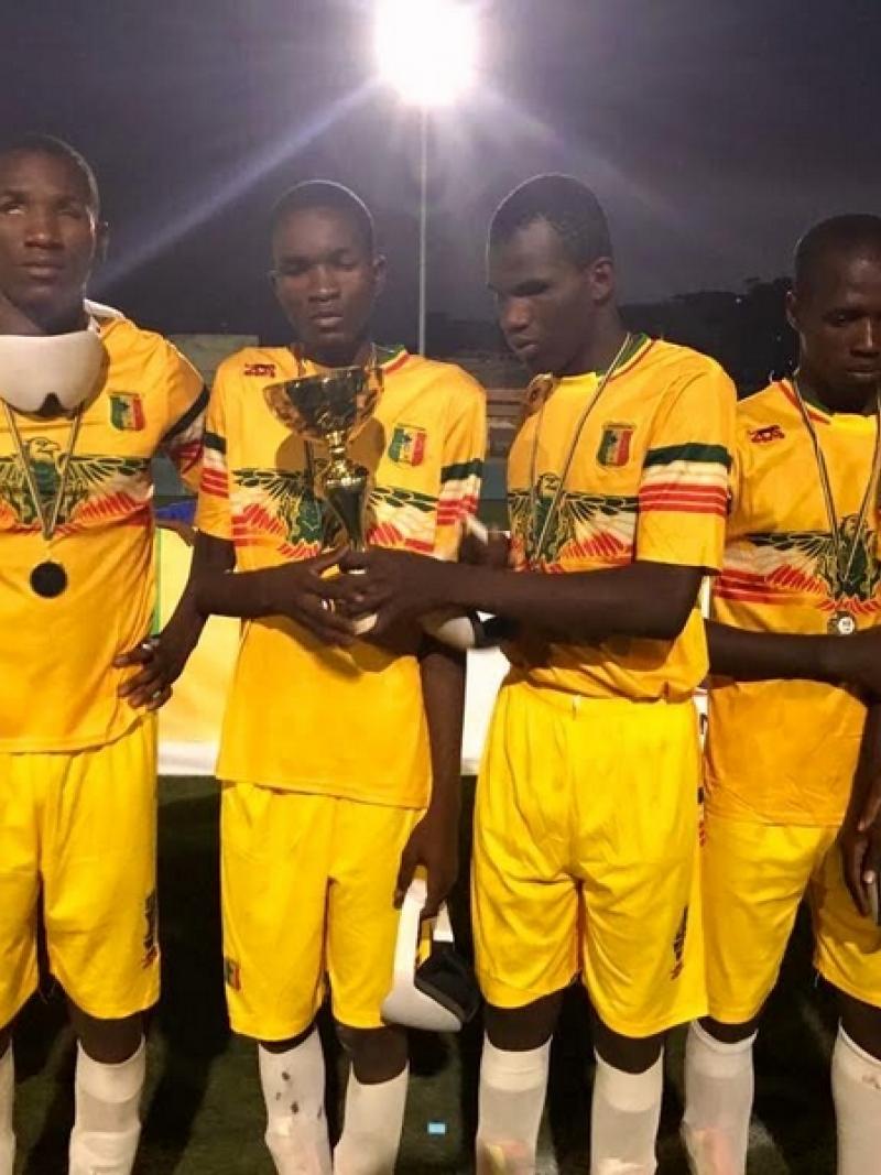 a group of blind footballers hold up a trophy