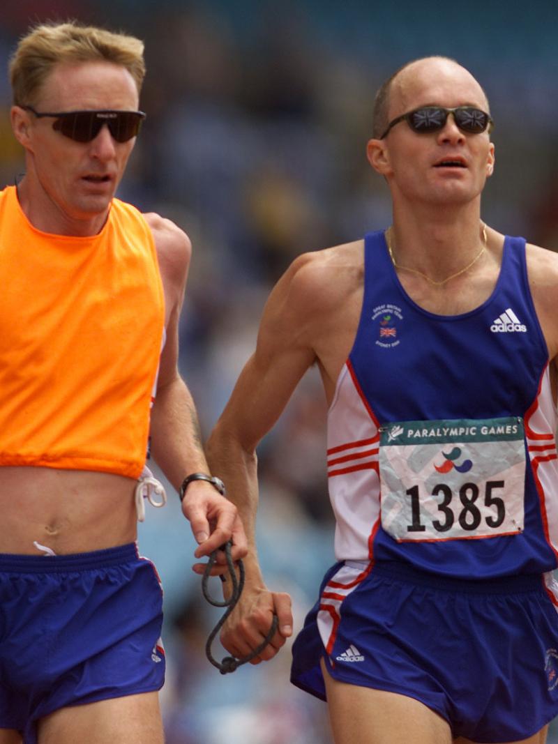 a male vision impaired runner and his guide during a race