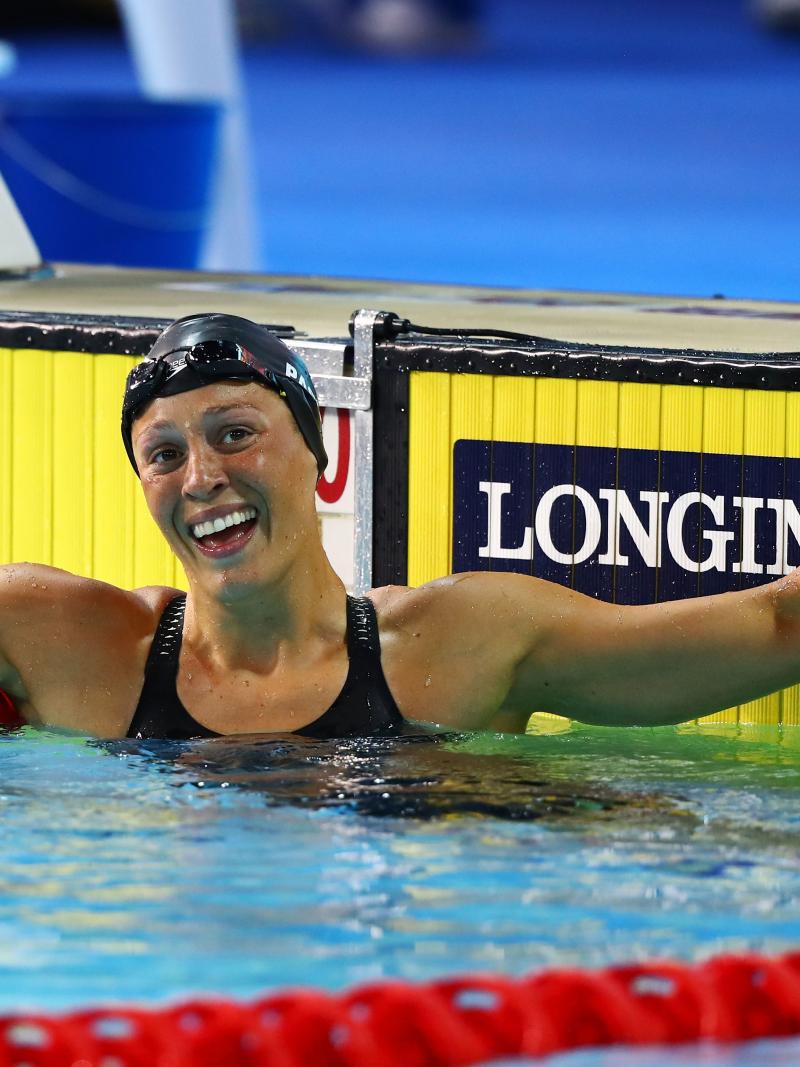 a female swimmer raises her arm in celebration in the pool