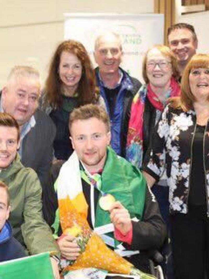 Man in wheelchair with Irish flag around him and his family