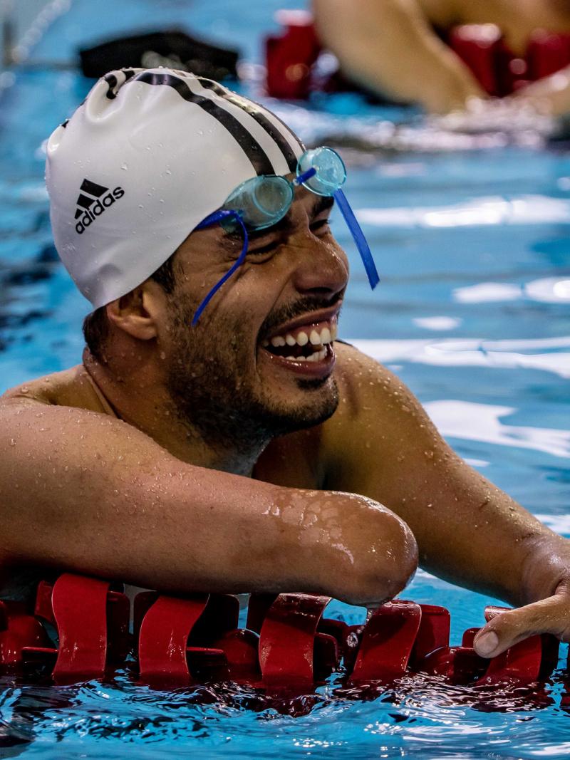 a male Para swimmer laughs in the pool