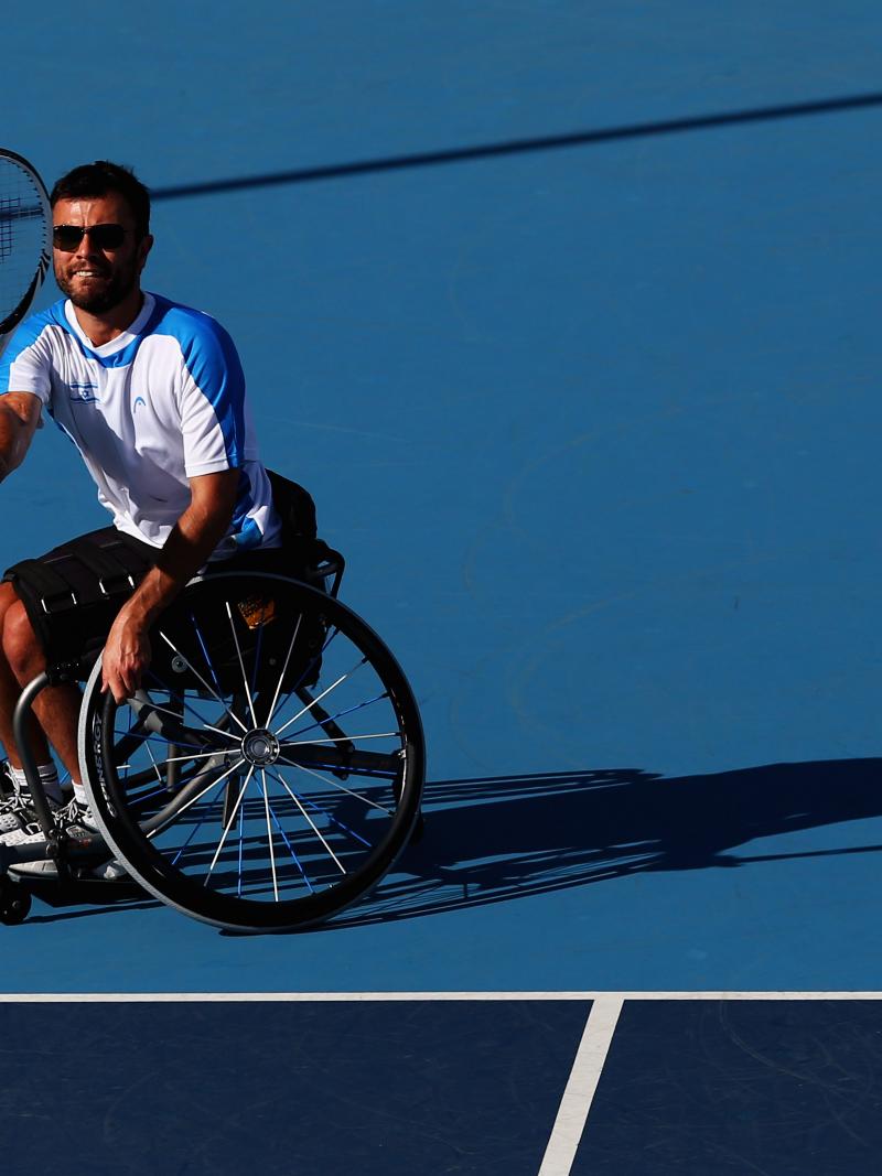A male wheelchair tennis player takes a shot