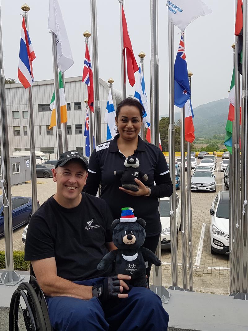 a male Para athlete and a woman standing both holding mascots