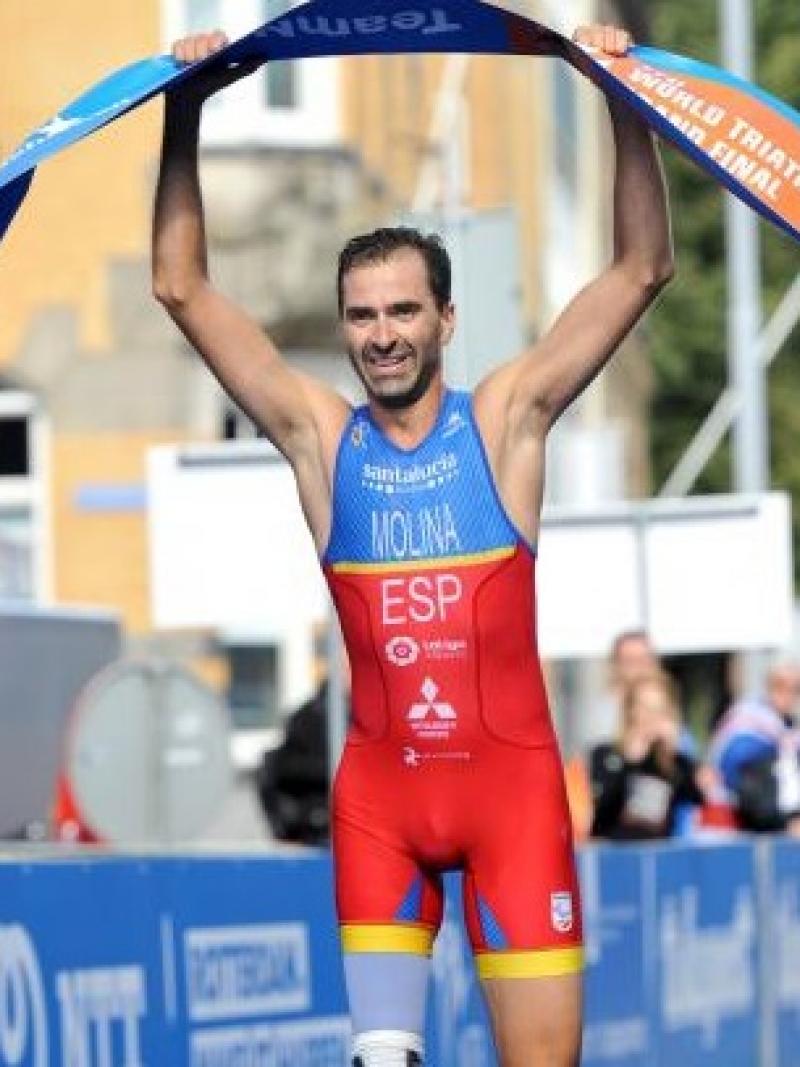 a male Para triathlete holds up the finish line tape as he crosses