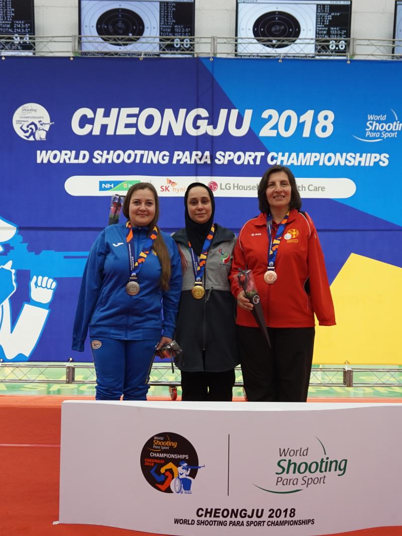 Three female shooting athletes pose on the podium