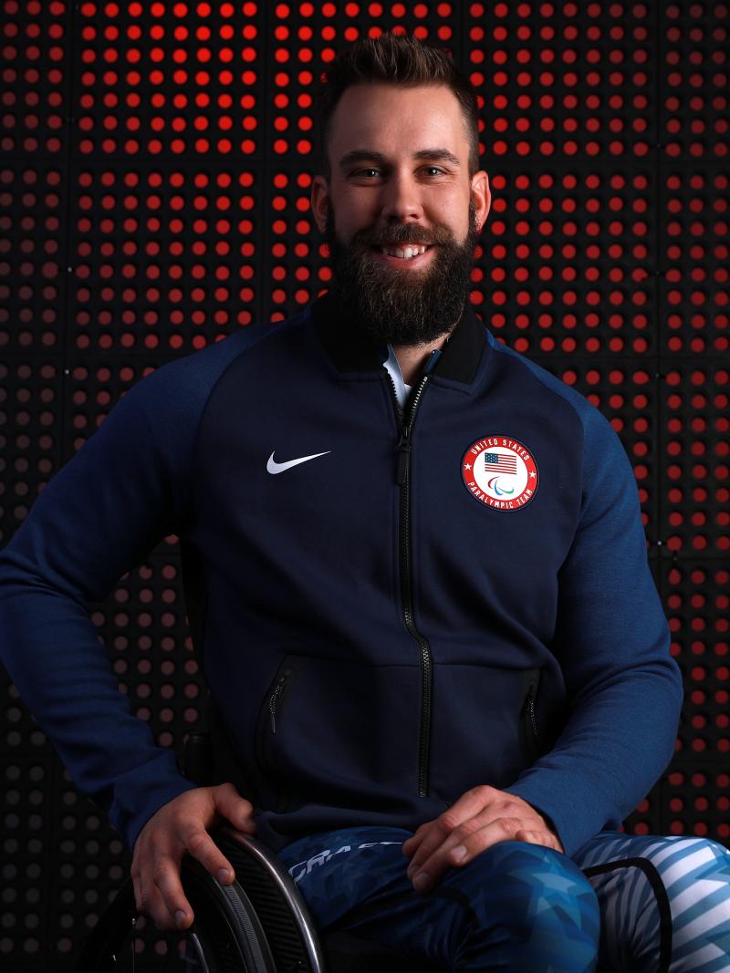 a male wheelchair athlete smiles at the camera