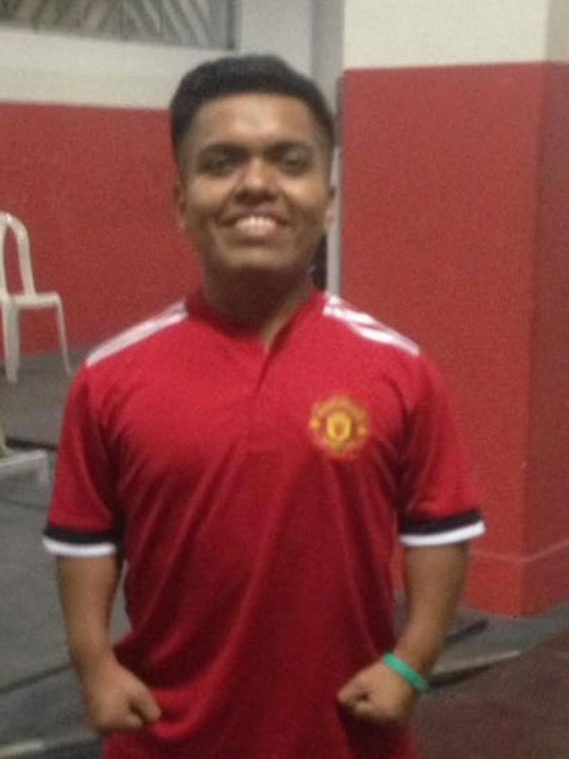 a male powerlifter standing in a Manchester United shirt