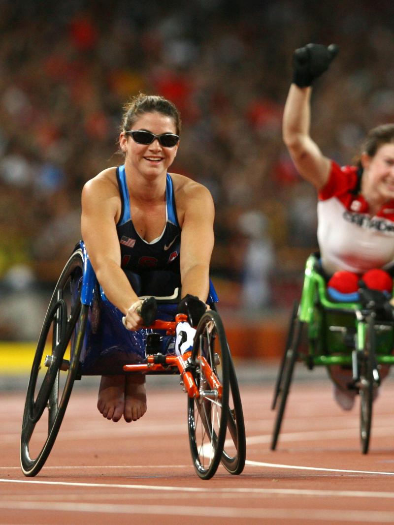 a female wheelchair racer celebrates after the finish line