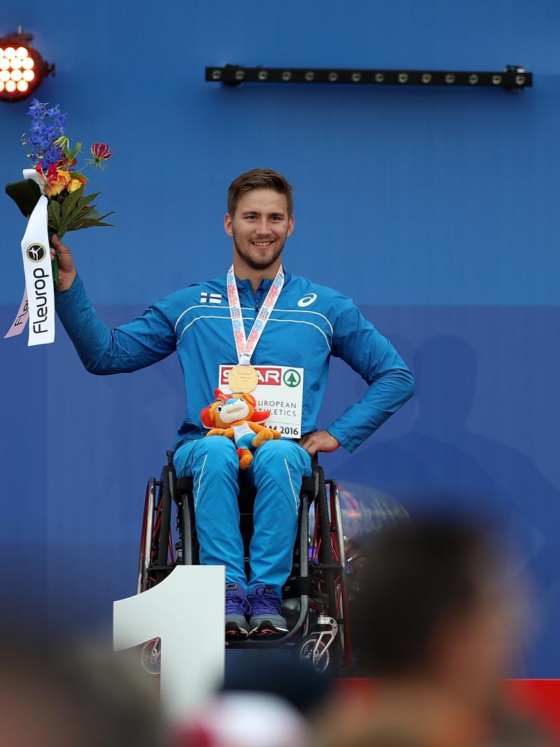 Person in a wheelchair on a podium holding flowers 