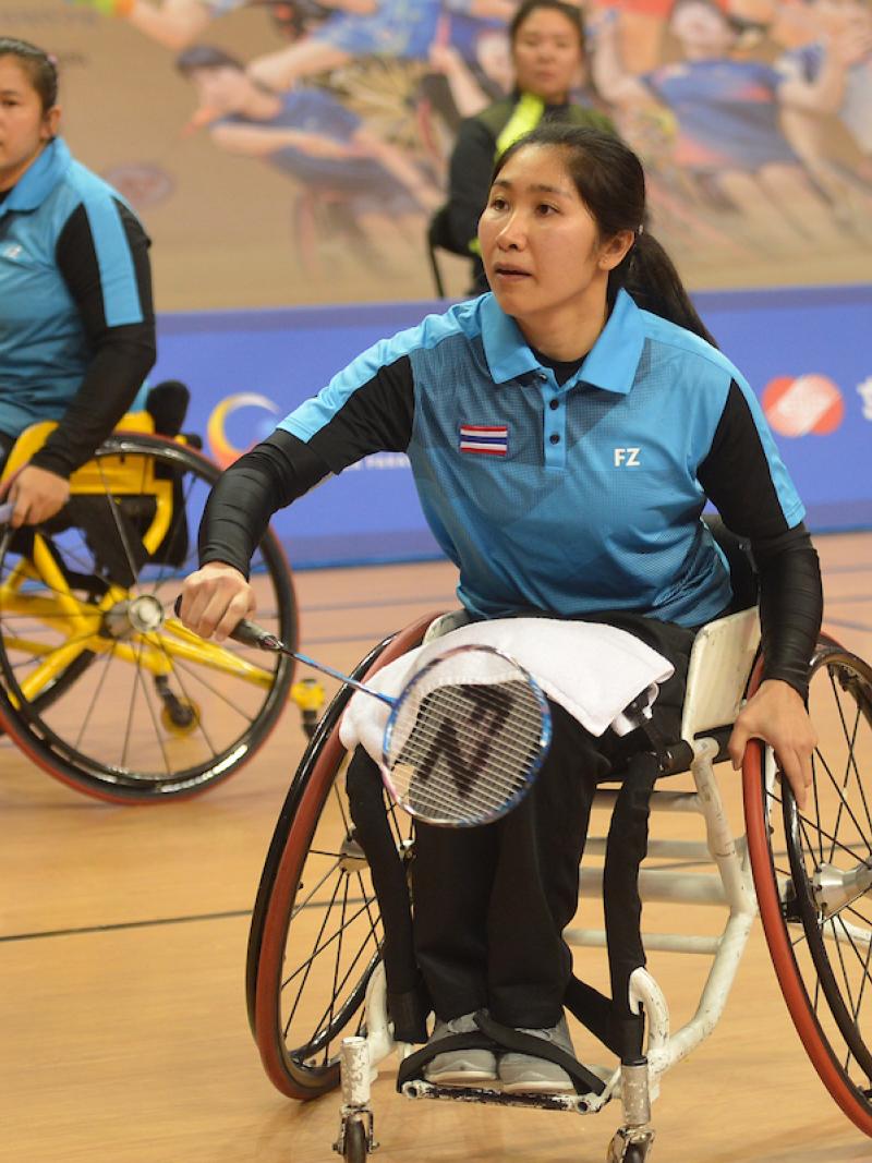 Woman badminton player in wheelchair hits a birdie