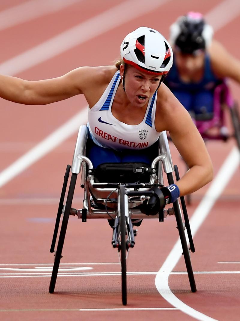 a female wheelchair racer punches the air as she crosses the line