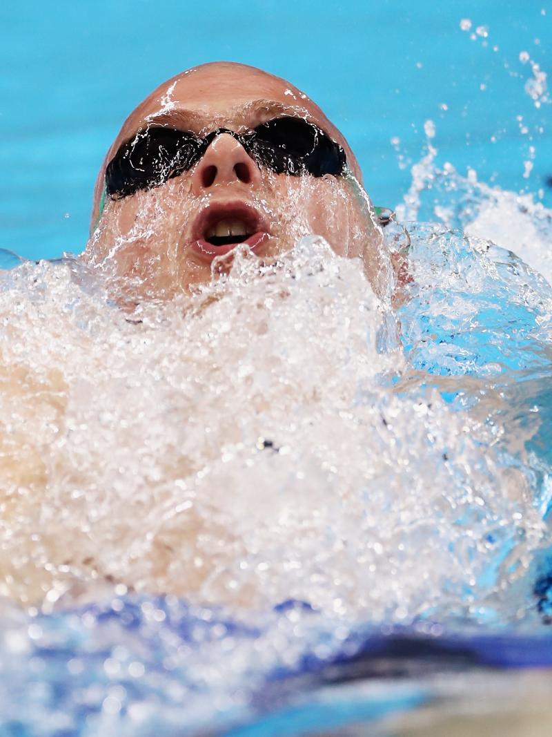 a male Para swimmer mid-backstroke