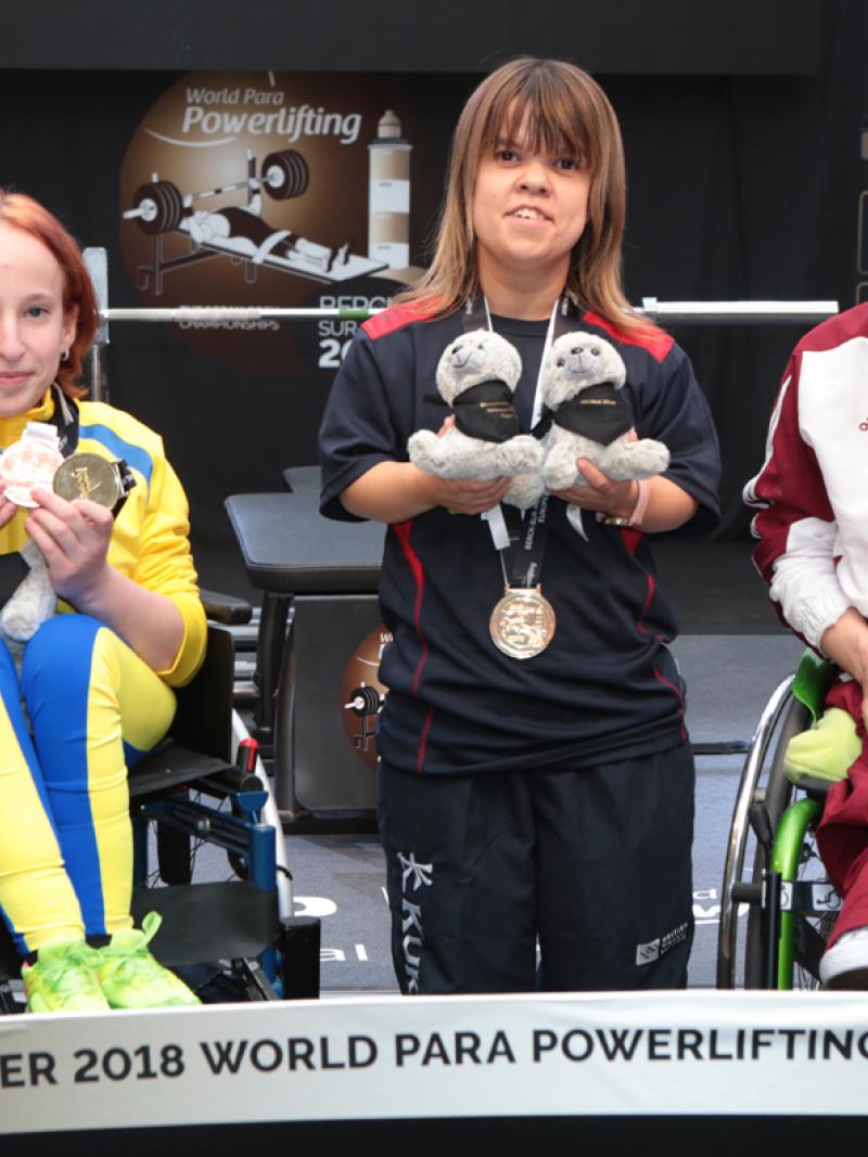 three female powerlifters on the podium