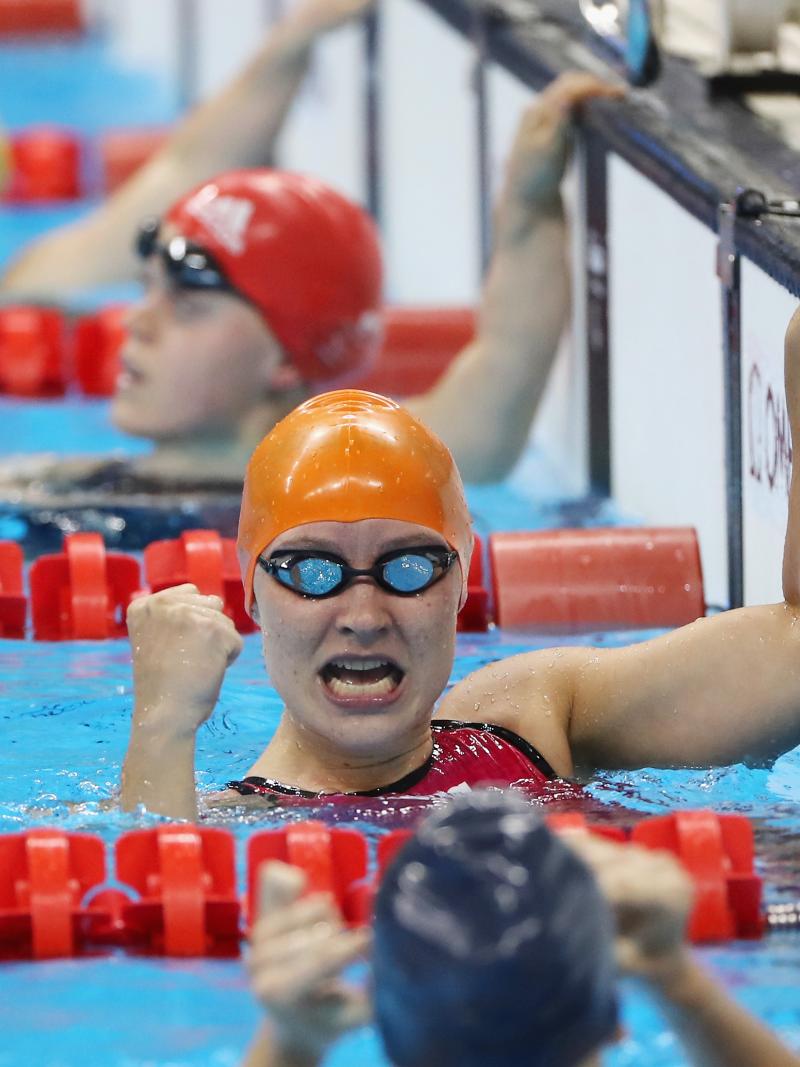 a female Para swimmer punches in the air in the pool