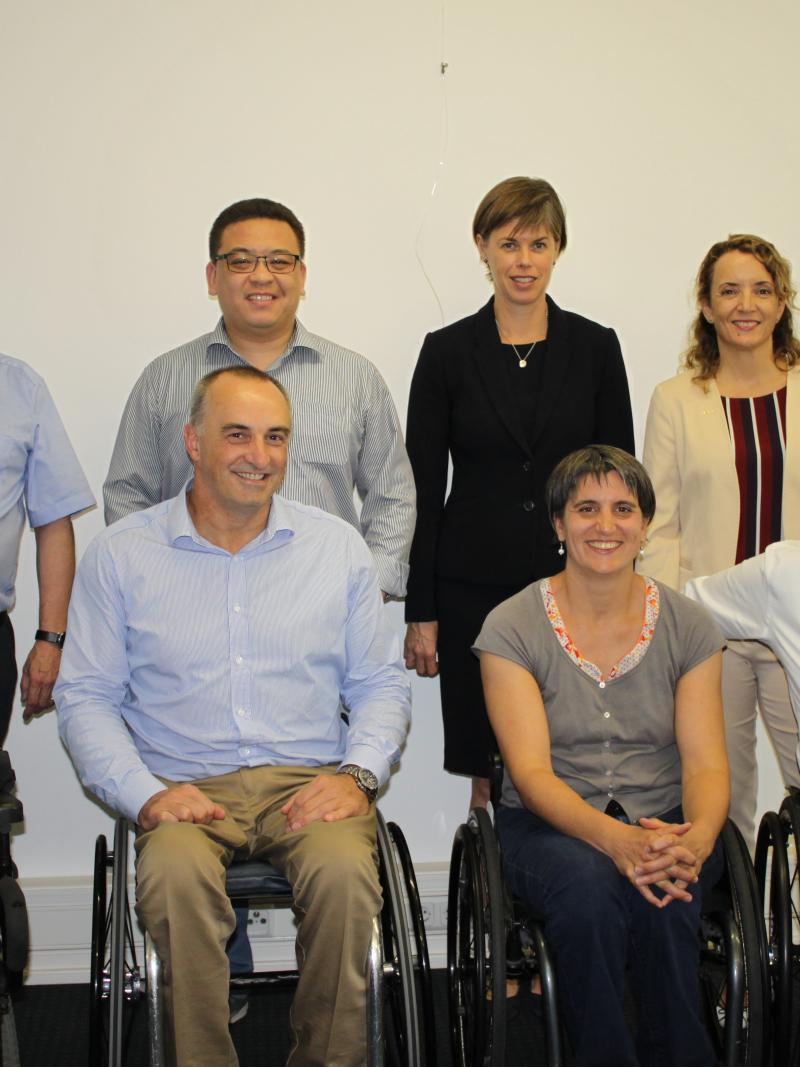 A group of eight people both standing and sitting smile for the camera