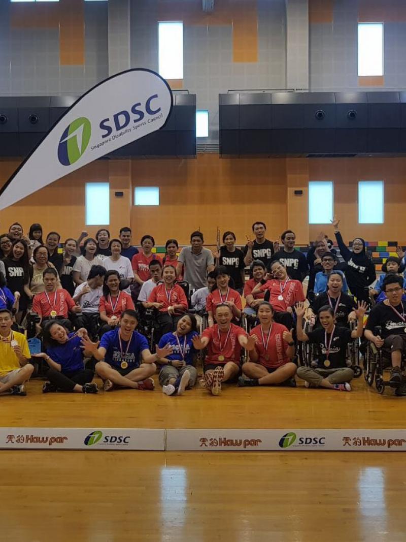 a group of boccia players and children sitting in a gym