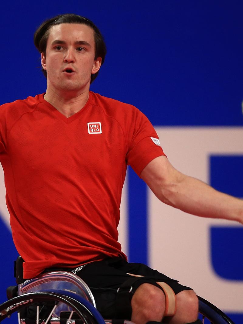 a male wheelchair tennis player takes a shot