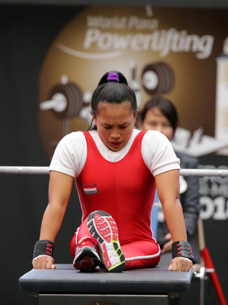 a female powerlifter prepares to lift by sitting on the bench