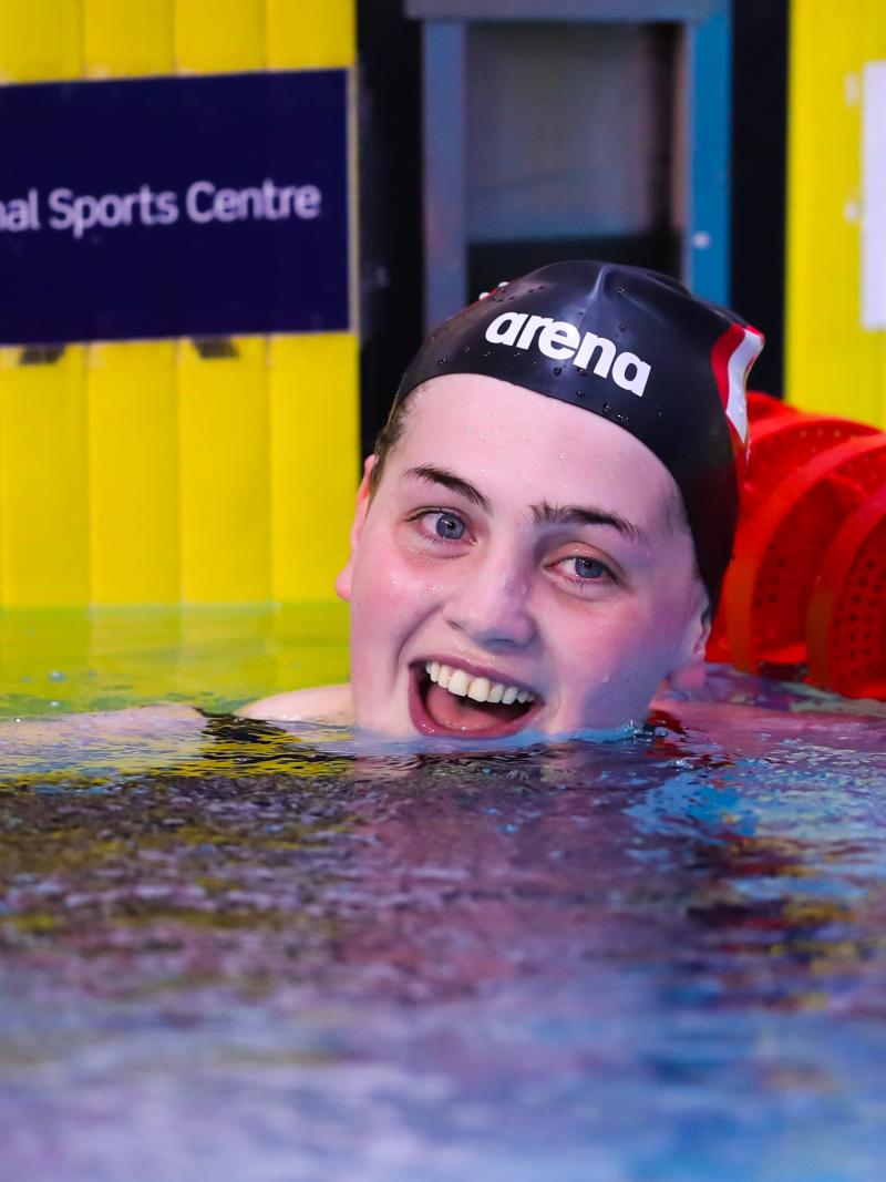 a female swimmer smiles in the pool after winning her race