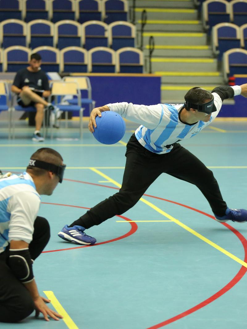a male goalball player prepares to take a shot while two others wait beside him