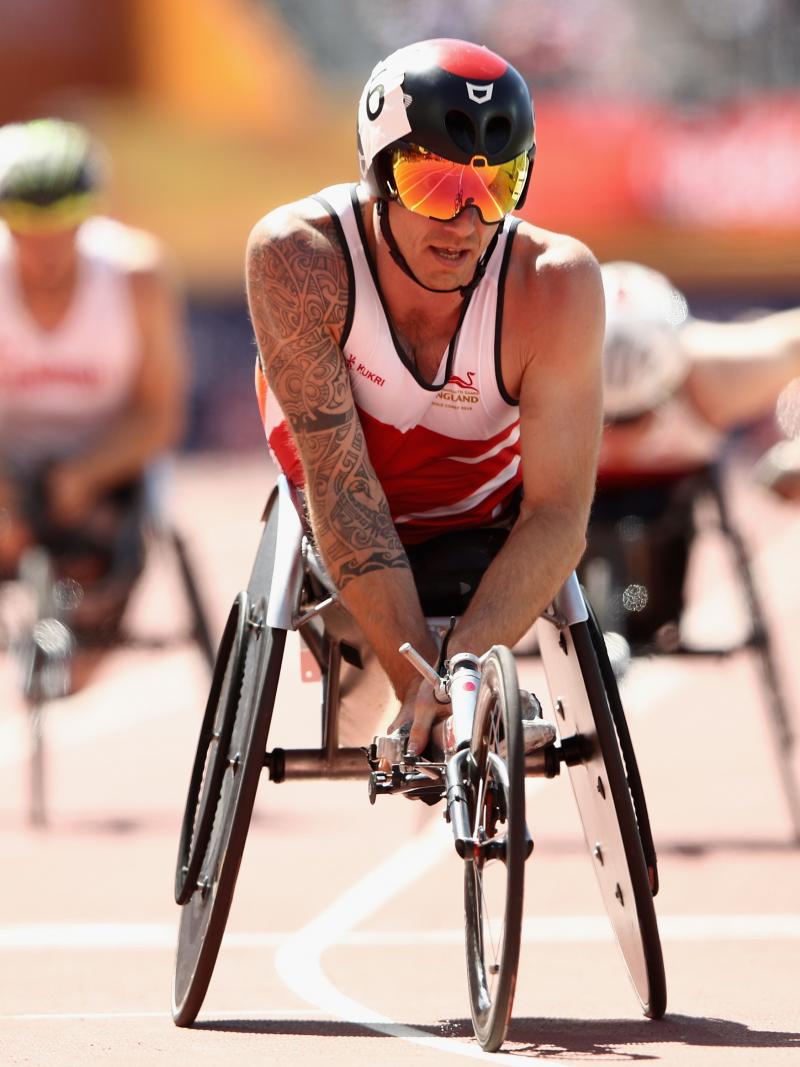 a male wheelchair racer crosses the finish line
