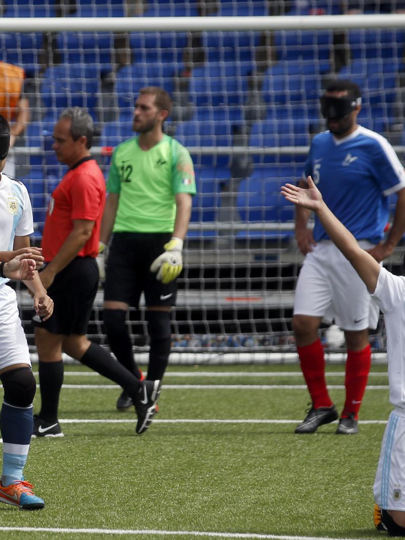 a male blind footballer celebrates on his knees after scoring a goal