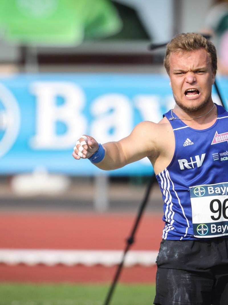 a male thrower of short stature launches a shot put