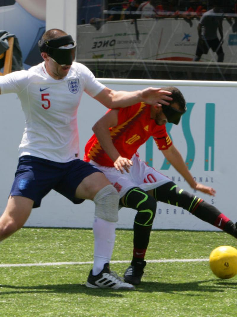 two male blind footballers battling for the ball 