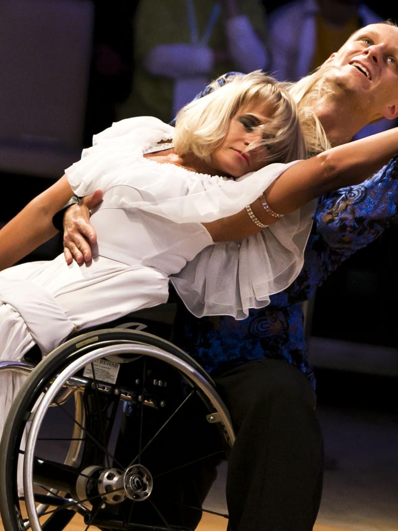 A female wheelchair dancer in a move with her able-bodied male partner