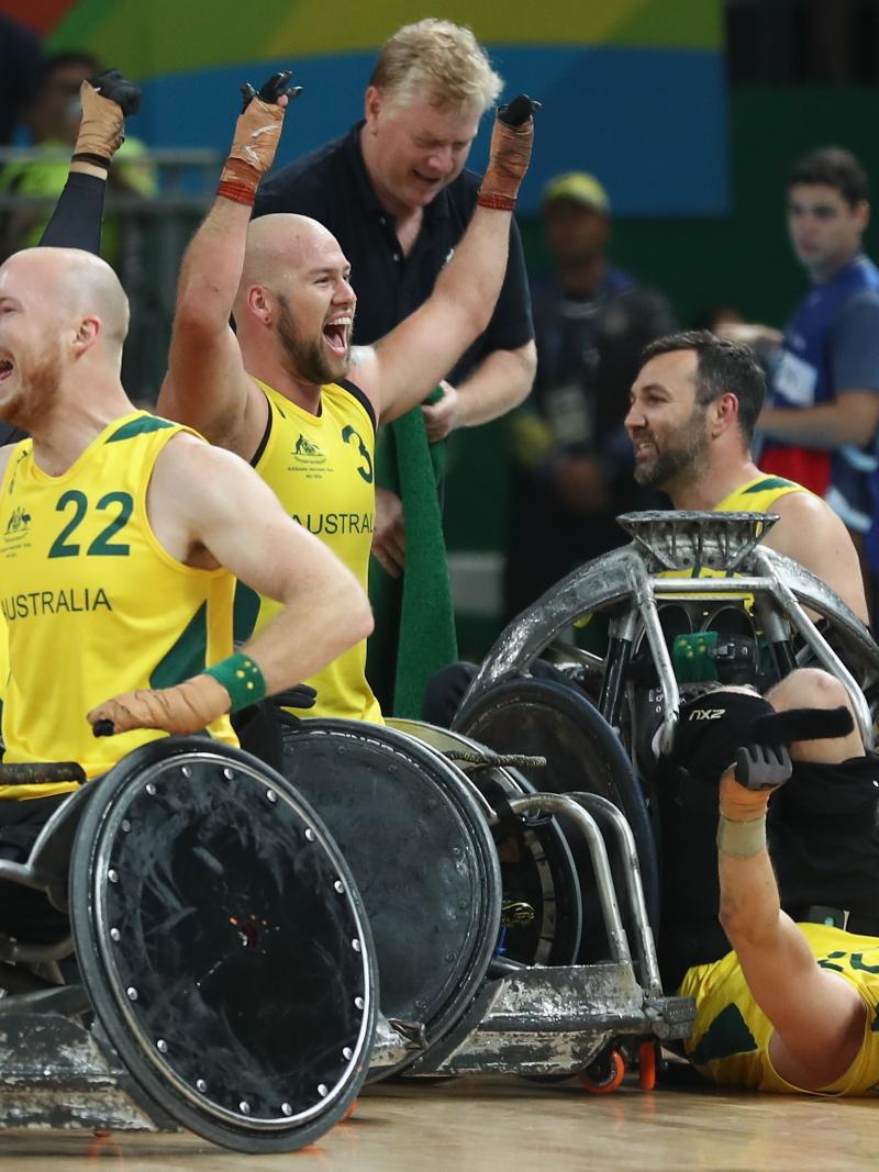 a group of male wheelchair rugby players celebrating on the court