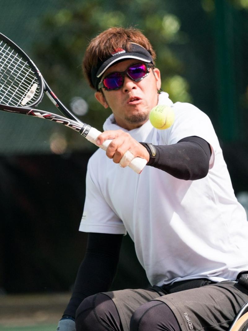 a male wheelchair tennis player goes for a backhand shot