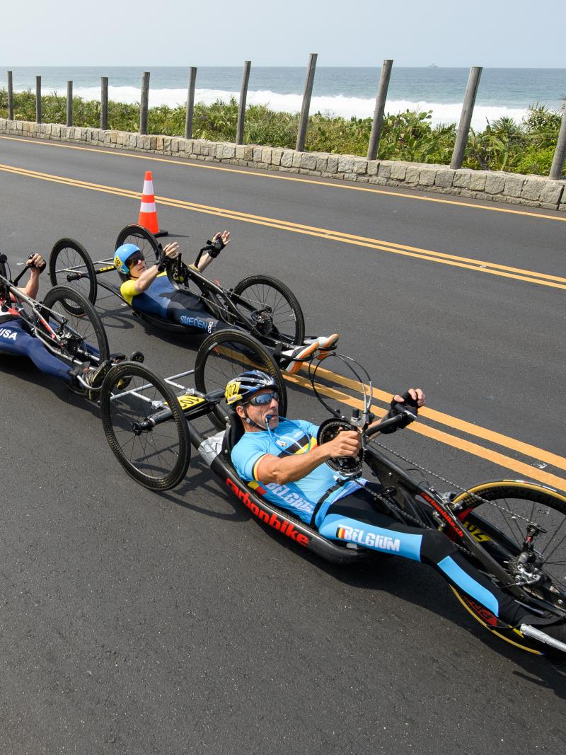 a group of male Para cyclists race along the road