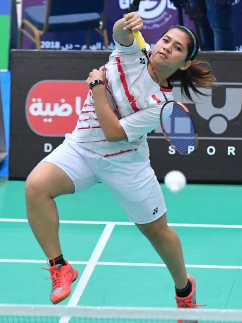 Female badminton player jumps to hit a birdie